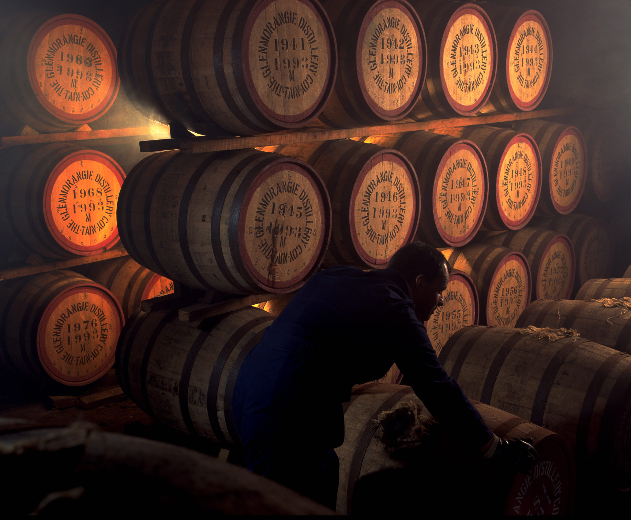 Man rolling barrels in Glenmorangie Whisky distillery, Scotland