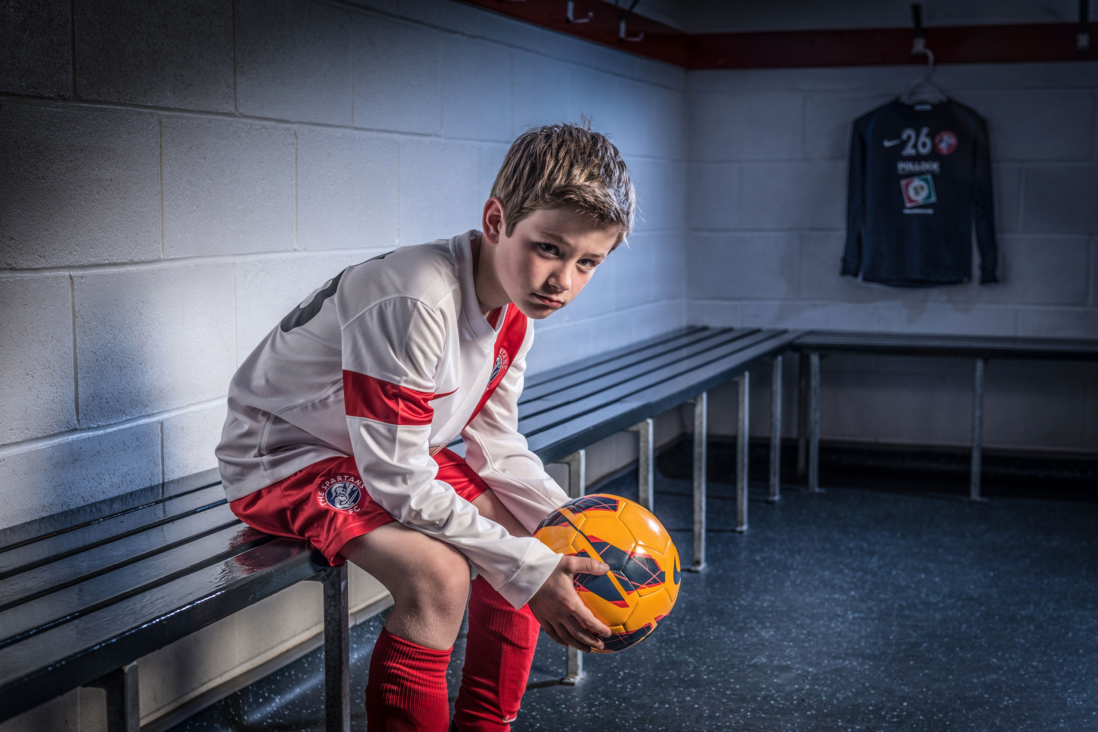 Young boy in football changing rooms holding football